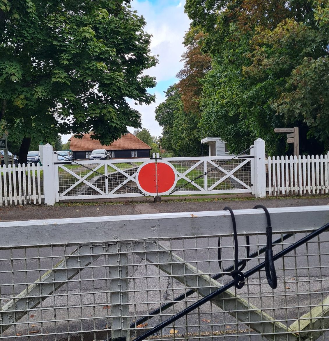 Across the road from the remains of Bramley & Wonersh station. On either side of the road are replica old white and red manual level crossing gates.