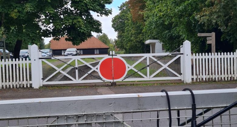 Across the road from the remains of Bramley & Wonersh station. On either side of the road are replica old white and red manual level crossing gates.